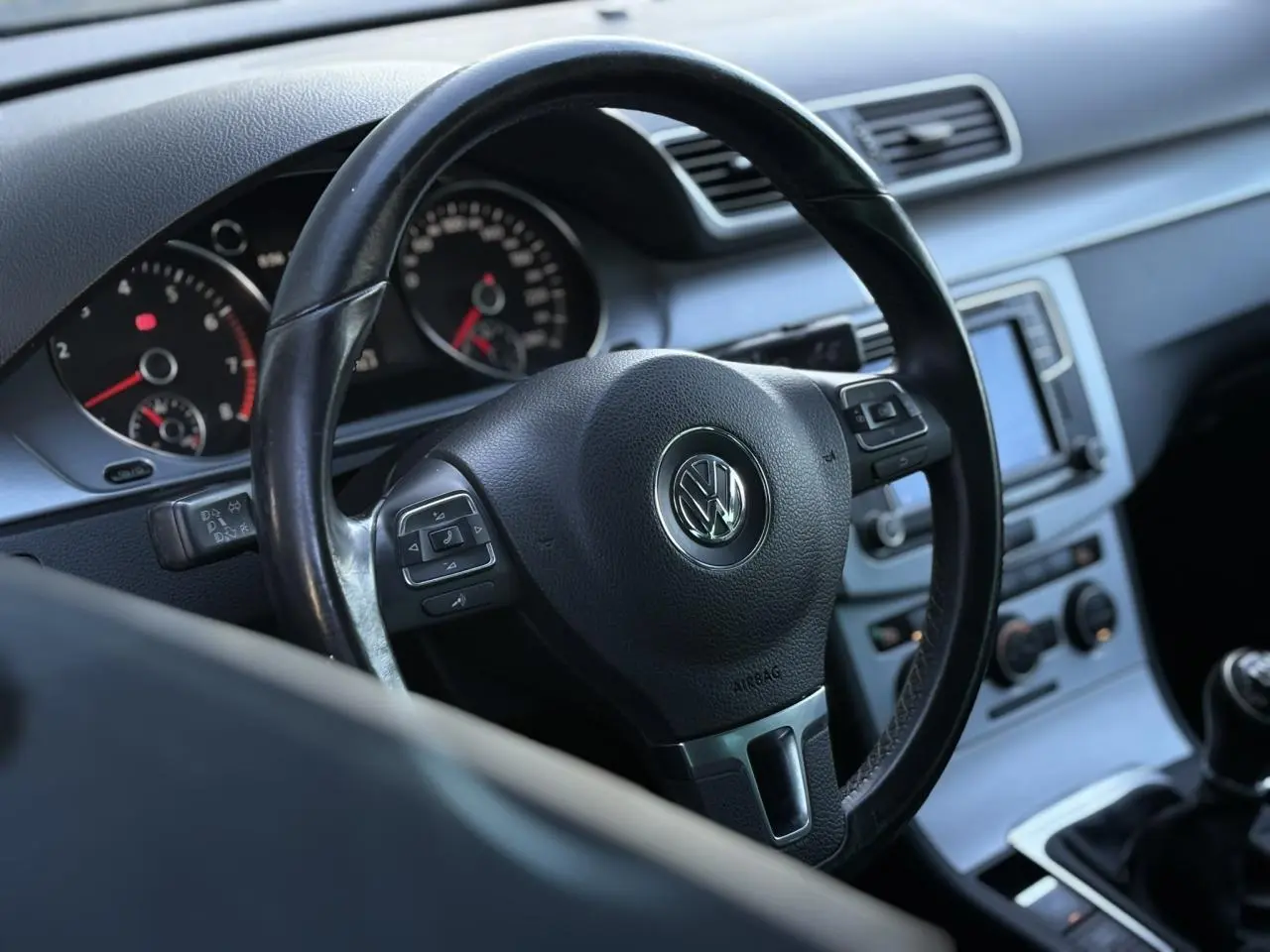 Vue rapprochée du volant en cuir noir multifonction de la Volkswagen Passat CC 2015 avec tableau de bord et console centrale visibles.