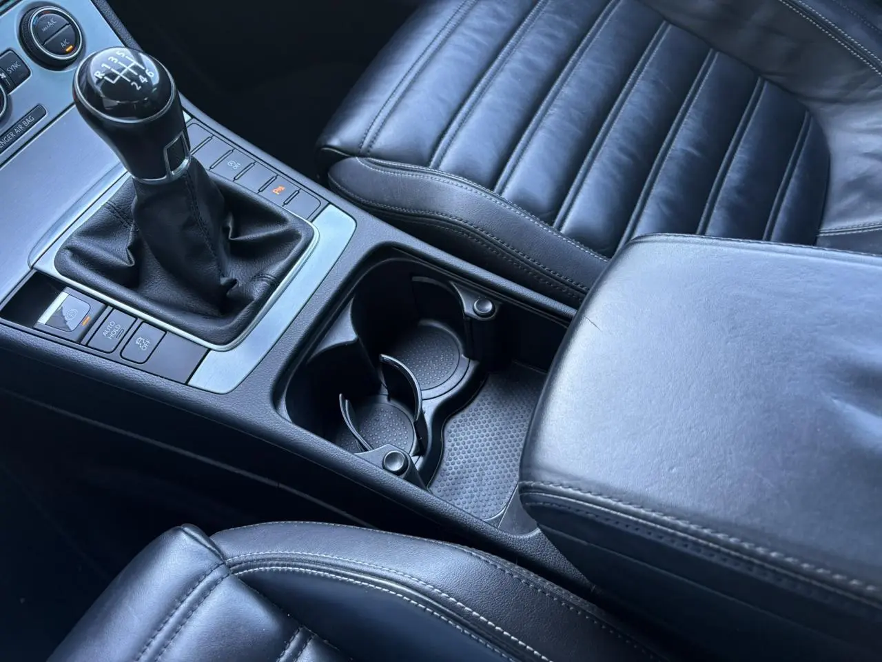 Gros plan intérieur sur la console centrale et la sellerie cuir noire de la Volkswagen Passat CC 1.4 TSI 2015 avec levier de vitesses manuel.