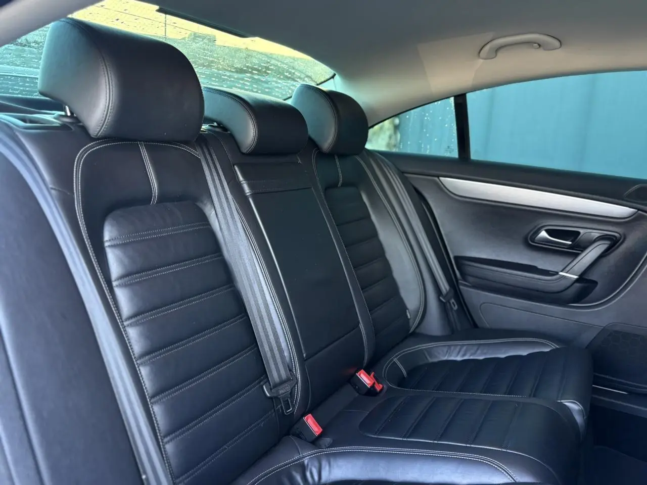 Vue intérieure des sièges arrière en cuir noir Nappa de la Volkswagen Passat CC 1.4 TSI 150 Carat, avec ceinture et accoudoir central.