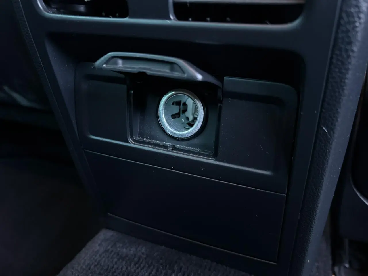 Gros plan sur la prise 12V du tableau de bord intérieur noir de la Volkswagen Passat CC 1.4 TSI Deep Black.