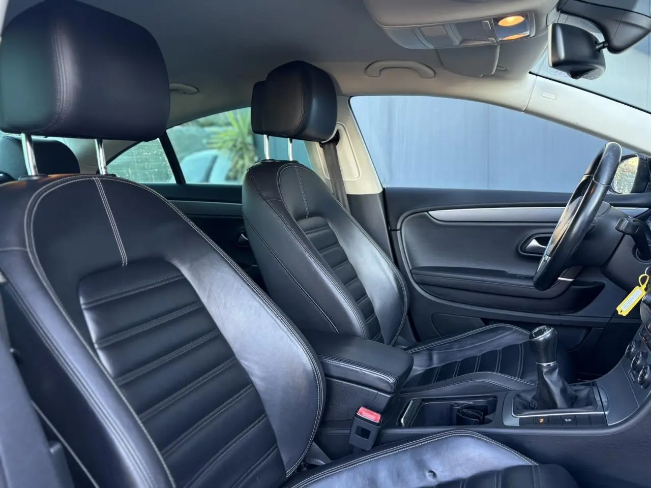 Vue intérieure côté conducteur de la Volkswagen Passat CC 1.4 TSI 2015 avec sellerie cuir Nappa noire et boîte manuelle.