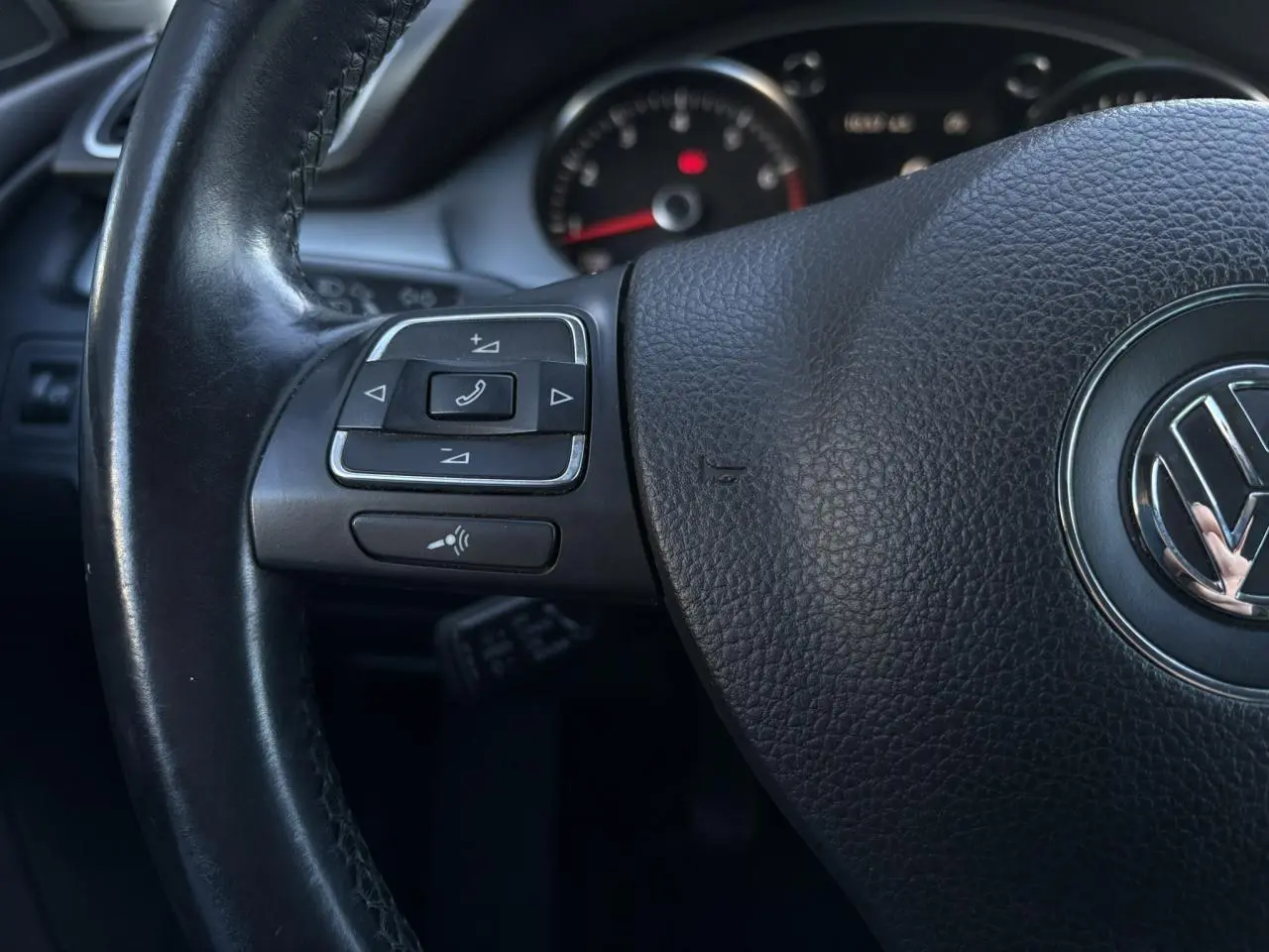 Gros plan sur le volant cuir multifonction noir de la Volkswagen Passat CC 2015 avec commandes intégrées.