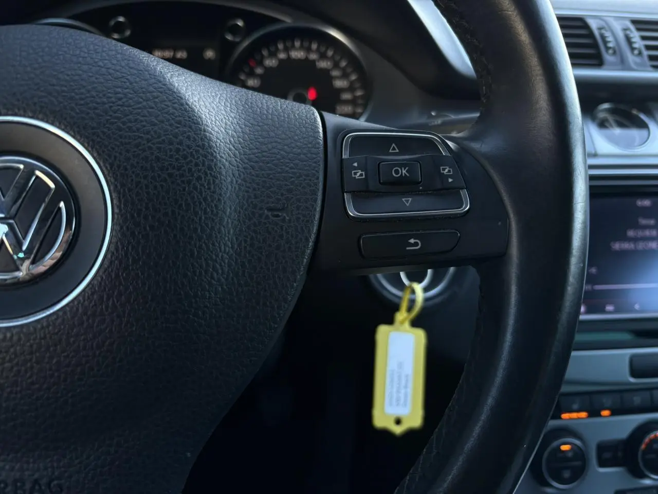 Gros plan sur le volant cuir multifonction de la Volkswagen Passat CC 1.4 TSI, avec commandes intégrées et tableau de bord en arrière-plan.