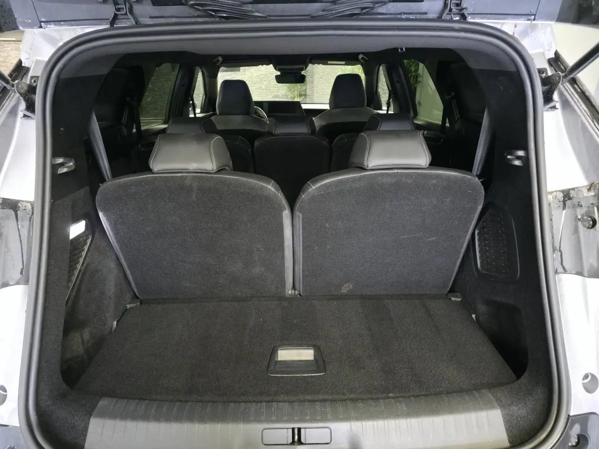Coffre ouvert vu de l'arrière d'un Peugeot 5008 gris 2025, banquette 3e rangée relevée et intérieur noir.