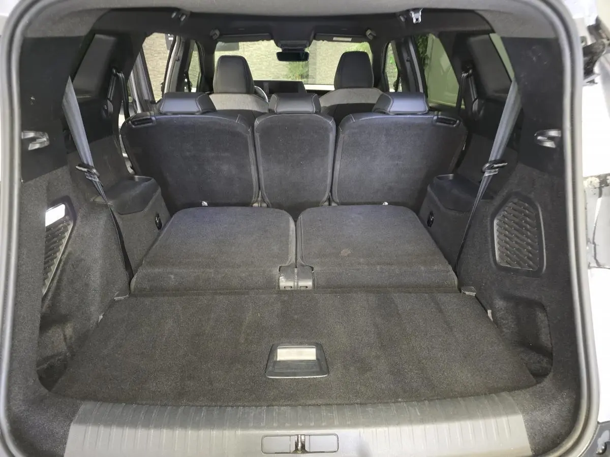 Vue du coffre arrière ouvert d’un Peugeot 5008 gris 2025 avec banquette rabattue et intérieur noir.