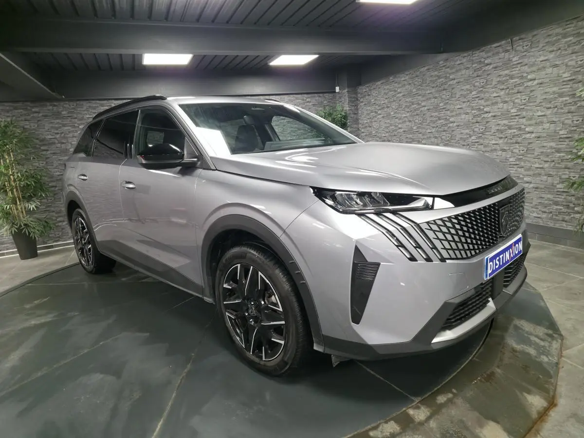 Peugeot 5008 gris métallisé vue 3/4 avant droit, avec calandre noire et jantes alliage 19 pouces noires.