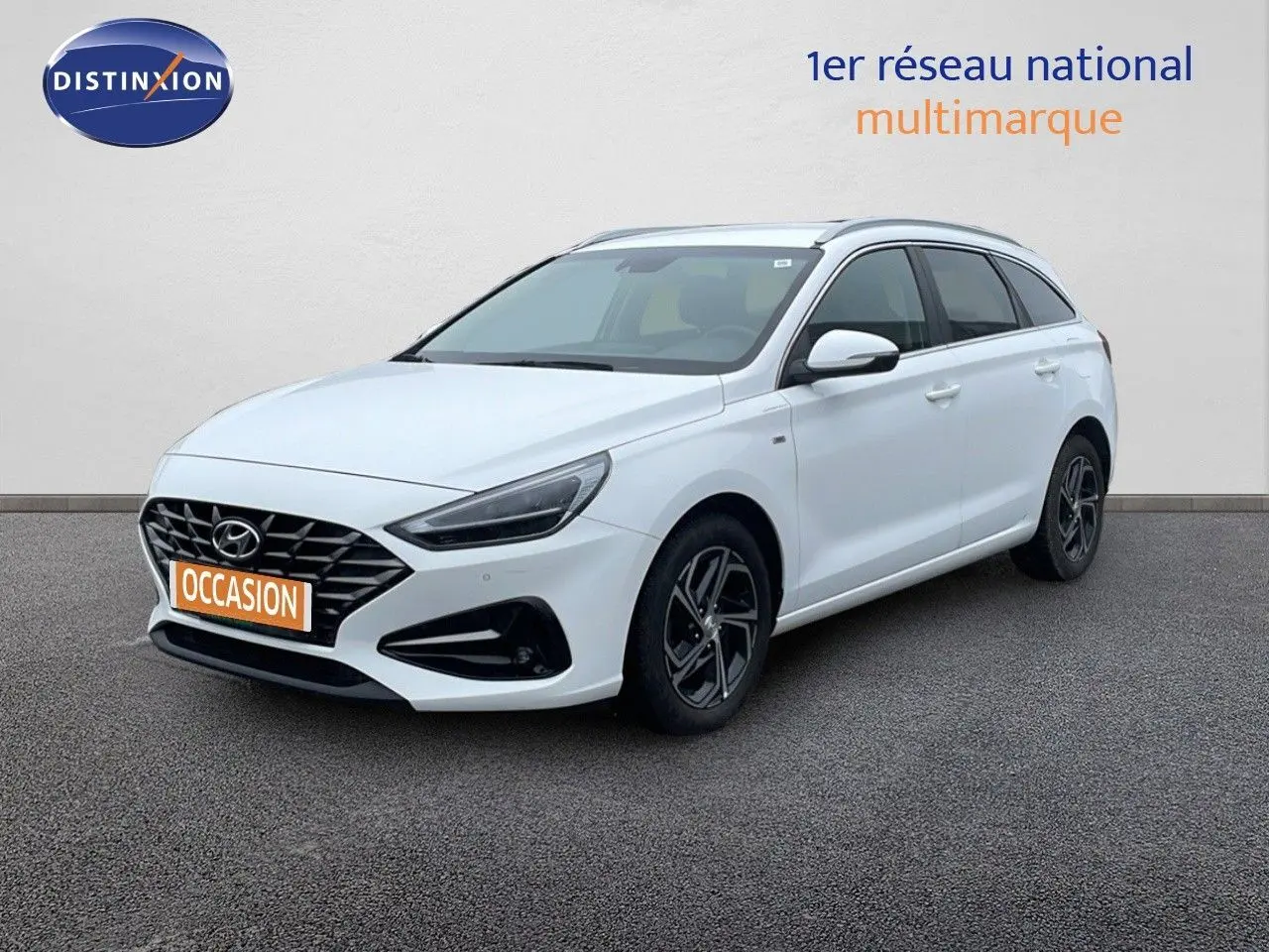 Hyundai i30 SW blanc polaire vue 3/4 avant droit, avec calandre noire et jantes alliage sombres.
