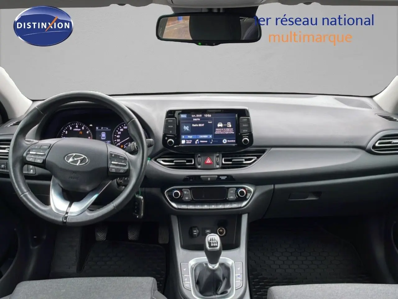 Vue intérieure avant de la Hyundai i30 SW 2021, tableau de bord gris noir avec écran tactile et boîte manuelle.