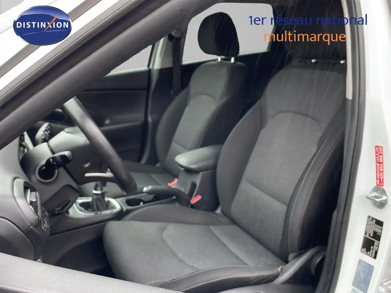 Vue intérieure côté conducteur de la Hyundai i30 SW blanche, sièges tissu gris foncé et volant multifonction.