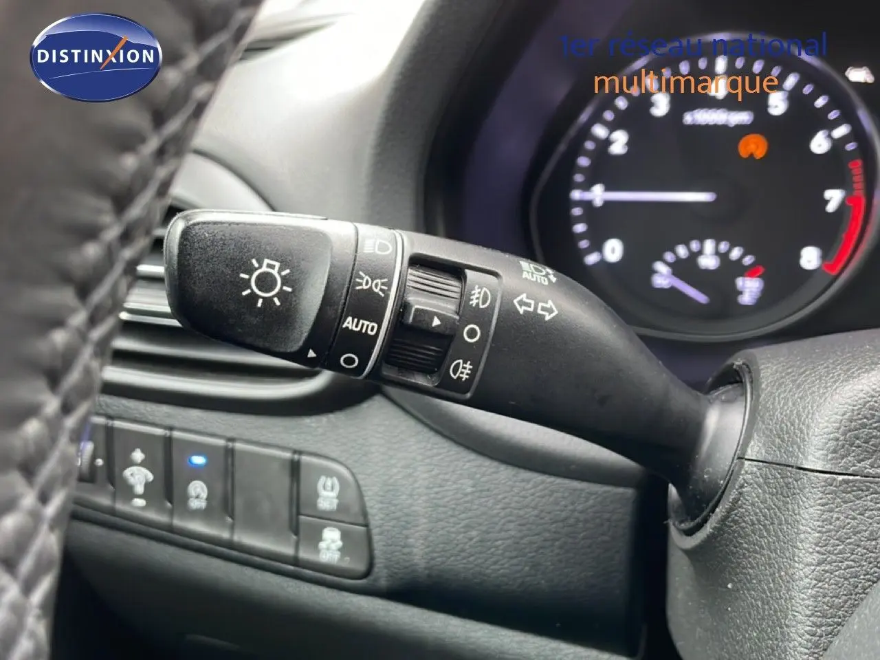 Gros plan sur la commande des feux et clignotants à gauche du volant dans l’habitacle noir d’une Hyundai i30 SW 2021.