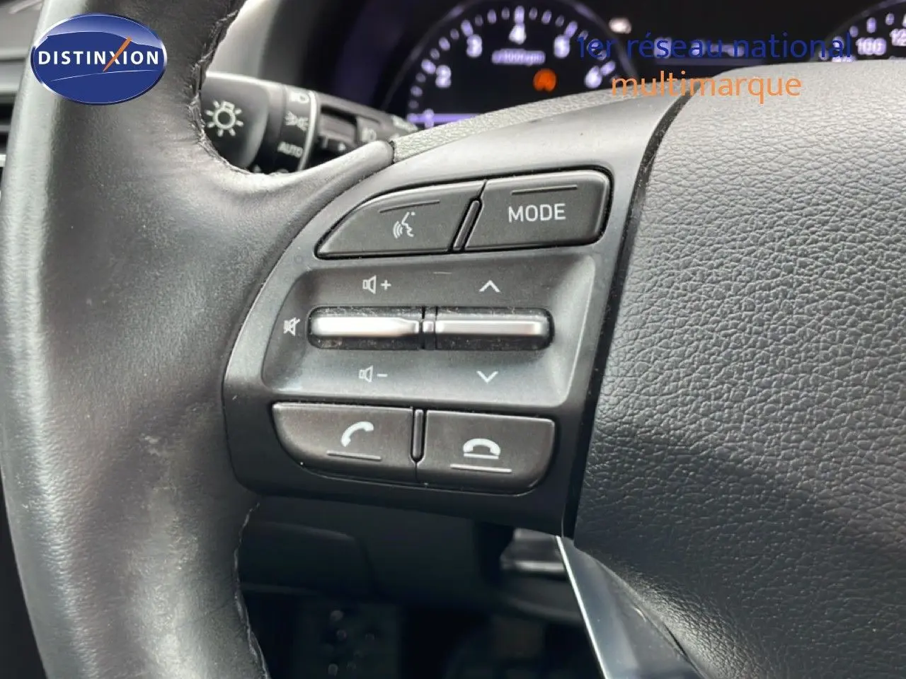 Gros plan sur les commandes au volant côté gauche de la Hyundai i30 SW blanc polaire, avec tableau de bord en arrière-plan flou.