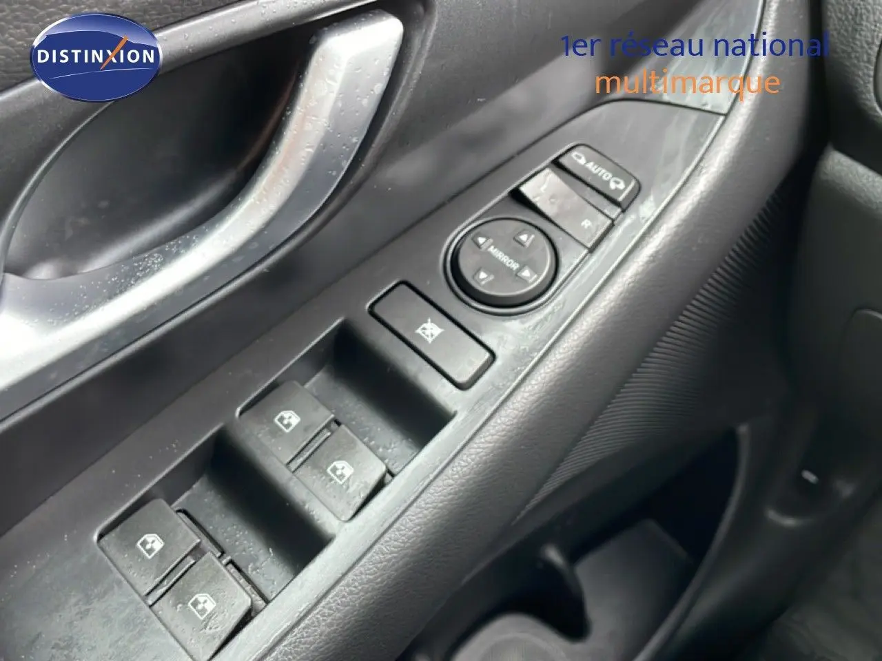 Gros plan sur la commande des vitres électriques côté conducteur d’une Hyundai i30 SW blanc polaire, intérieur noir.