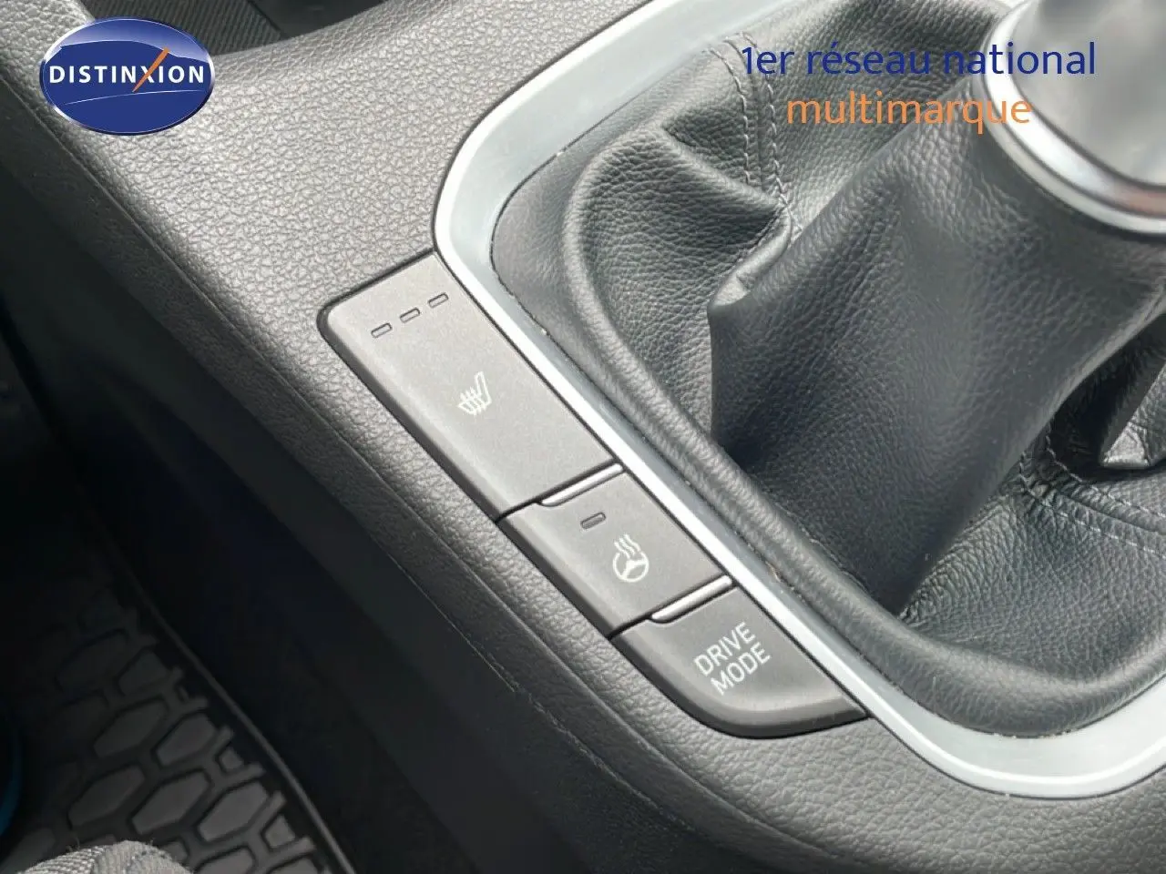 Gros plan sur la console centrale noire de la Hyundai i30 SW blanche, montrant le levier de vitesses manuel et les boutons de chauffage et mode de conduite.
