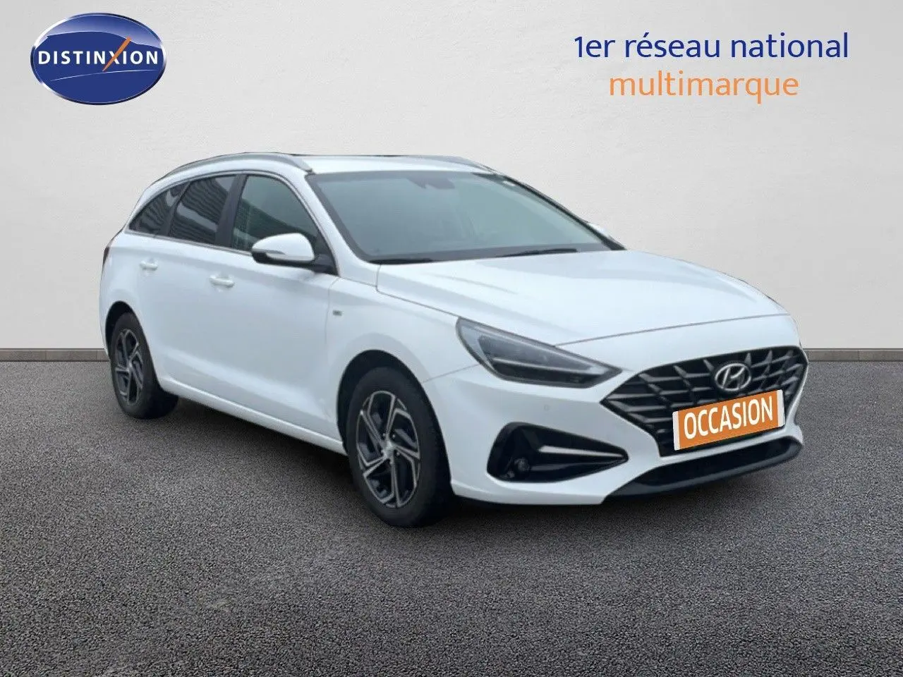 Vue 3/4 avant d'une Hyundai i30 SW blanche polaire avec calandre noire et jantes alliage bicolores.