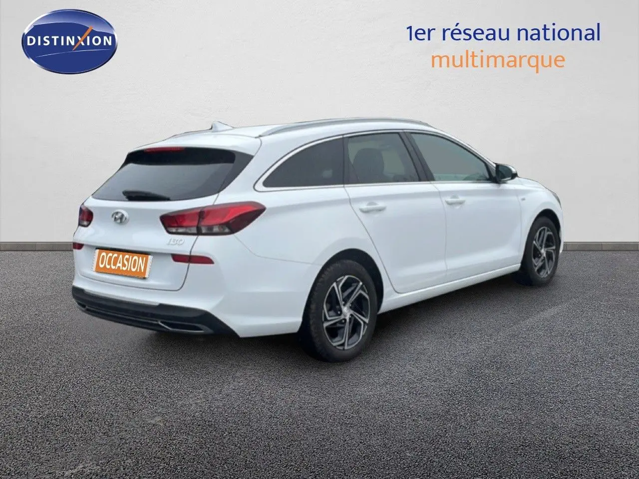 Vue 3/4 arrière droite d'une Hyundai i30 SW blanche polaire avec vitres teintées et jantes alliage noires.
