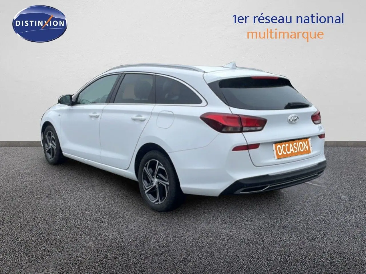 Vue 3/4 arrière droite d'une Hyundai i30 SW blanche polaire, break compact avec vitres teintées et jantes alliage.