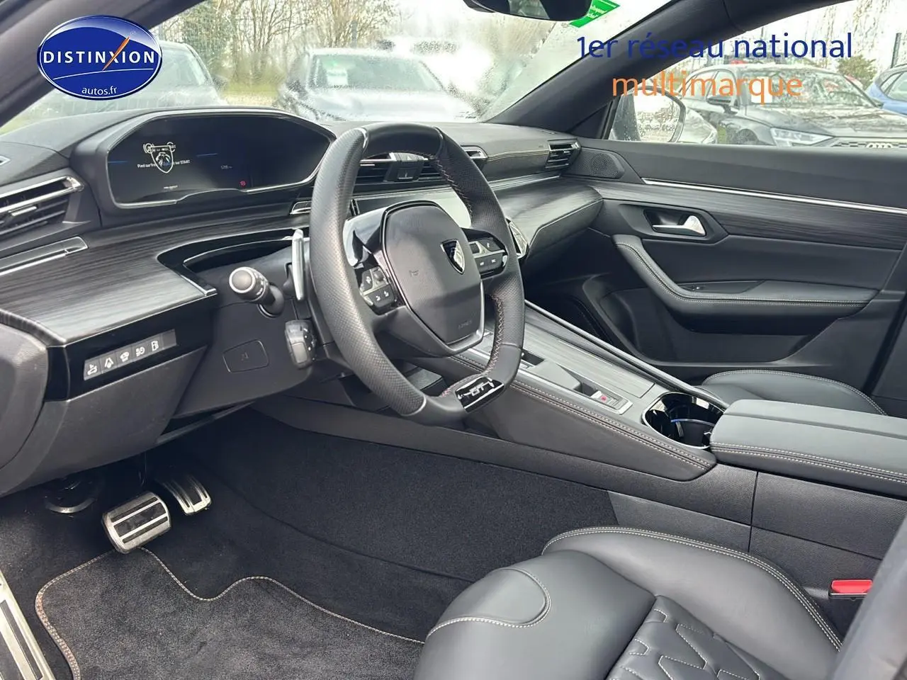 Vue intérieure côté conducteur du Peugeot 508 SW Hybrid 225 GT e-EAT8 avec volant cuir et inserts carbone.