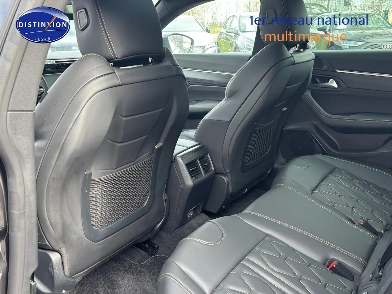 Vue intérieure arrière montrant les sièges en cuir noir et les aérateurs centraux d'une Peugeot 508 SW gris titane 2024.