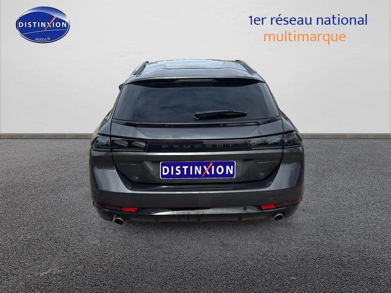 Vue arrière d'un Peugeot 508 SW Hybrid gris titane avec vitres arrière surteintées et double sortie d'échappement.