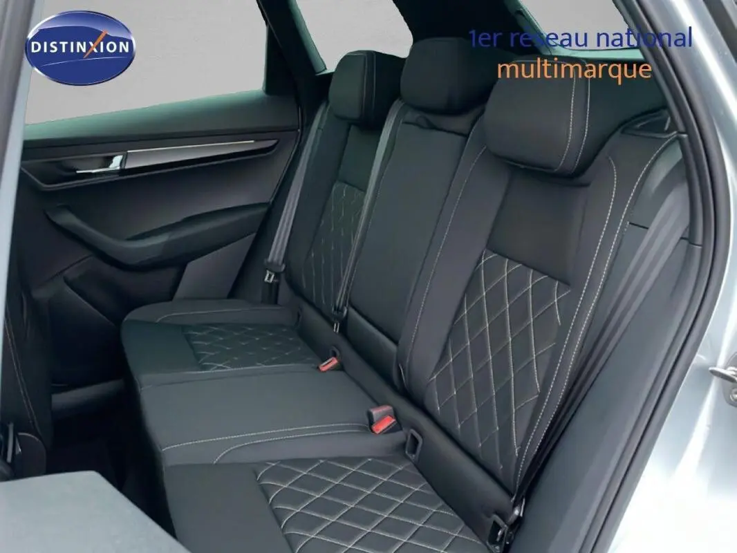 Vue intérieure montrant la banquette arrière en cuir noir avec surpiqûres, porte ouverte côté droit d’un Skoda Karoq argent.