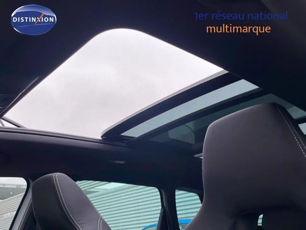 Vue intérieure montrant le toit panoramique ouvert et les sièges avant en cuir noir du Skoda Karoq argent 2025.