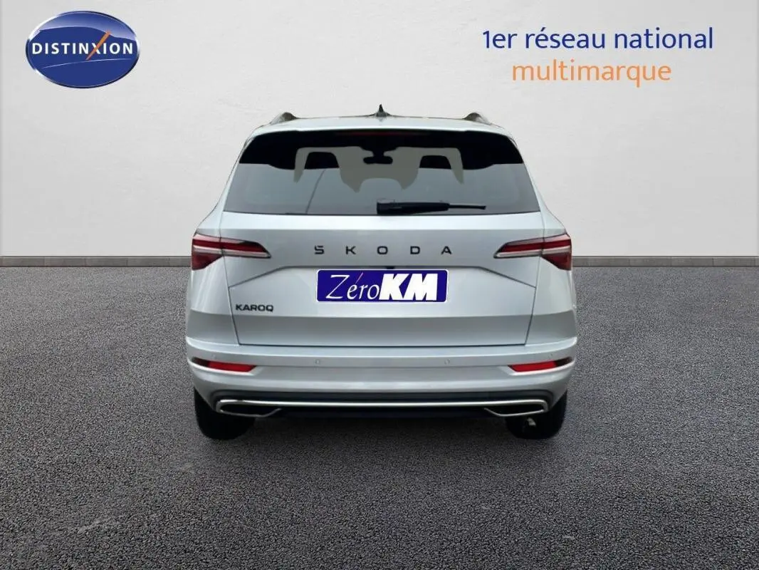 Vue arrière d'un Skoda Karoq argent 2025 avec barres de toit et feux LED fins, sur fond neutre.