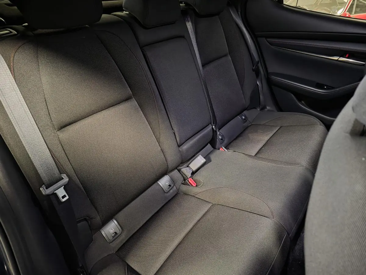 Vue intérieure des sièges arrière en tissu noir avec surpiqûres rouges de la Mazda3 2024, côté droit.