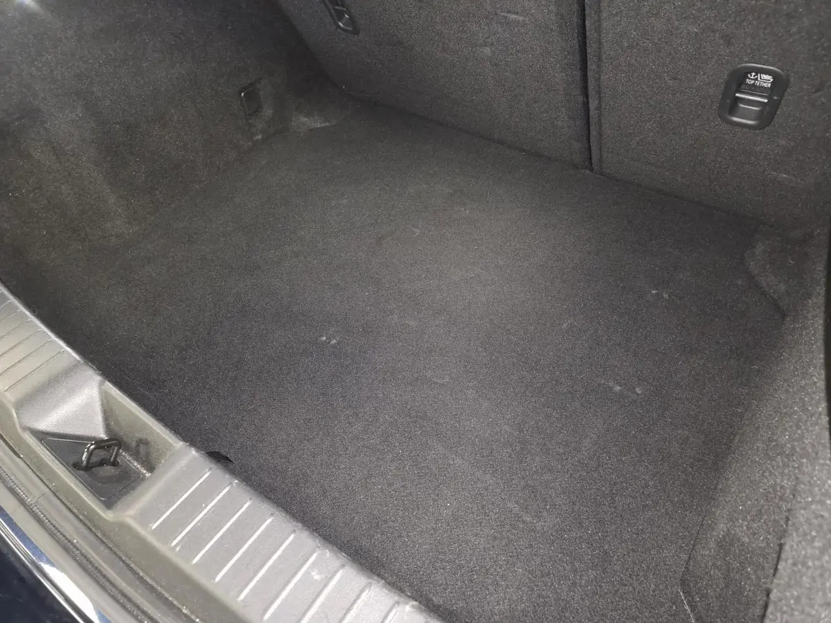 Vue intérieure du coffre spacieux et propre de la Mazda3 2024, revêtement noir uniforme sans objets visibles.