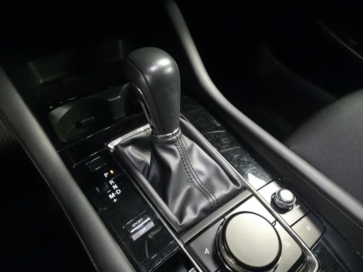 Gros plan sur la console centrale de la Mazda3 2024 bleue, montrant levier de vitesses automatique et commandes multimédia.