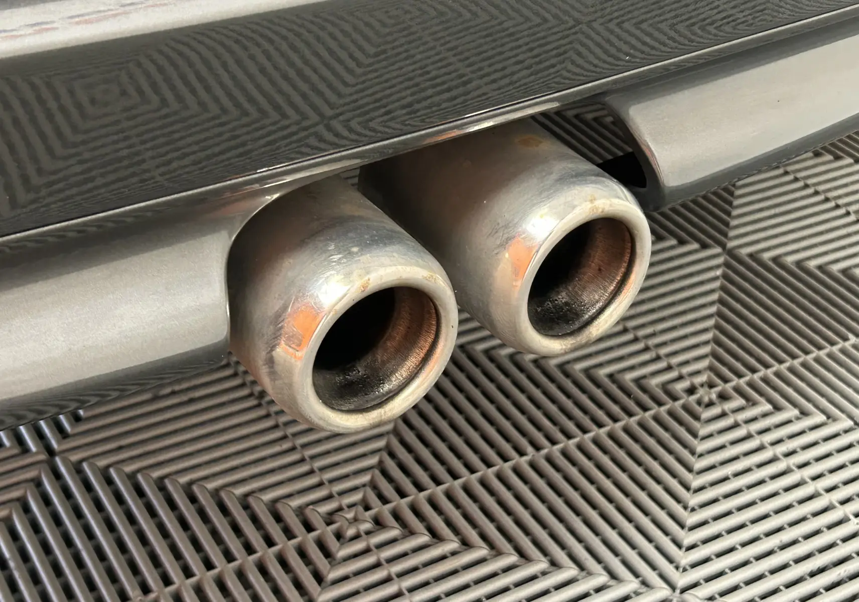 Gros plan sur les deux sorties d’échappement chromées à l’arrière d’une MINI Cooper gris métallisé.
