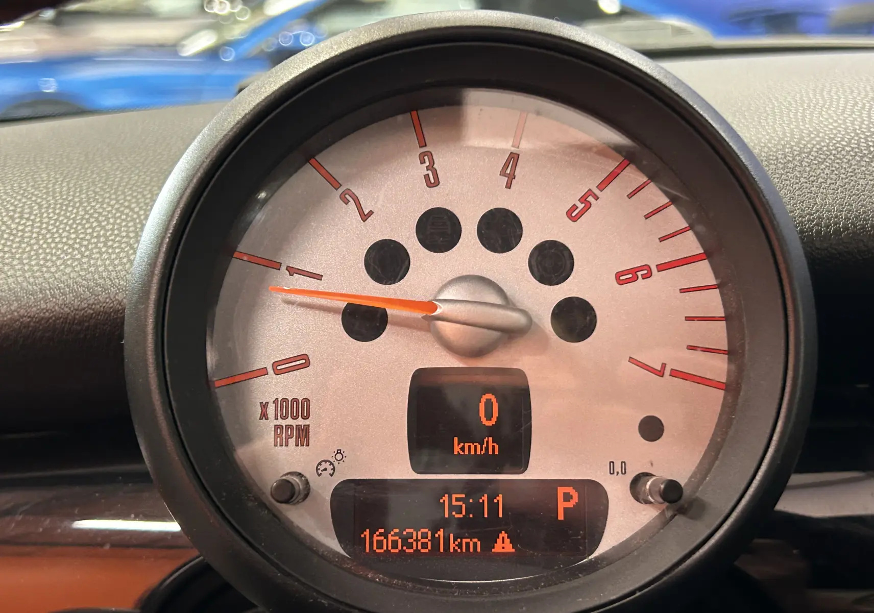 Gros plan sur le compteur central gris de la MINI Cooper Diesel, affichant 0 km/h et 166381 km au tableau de bord.