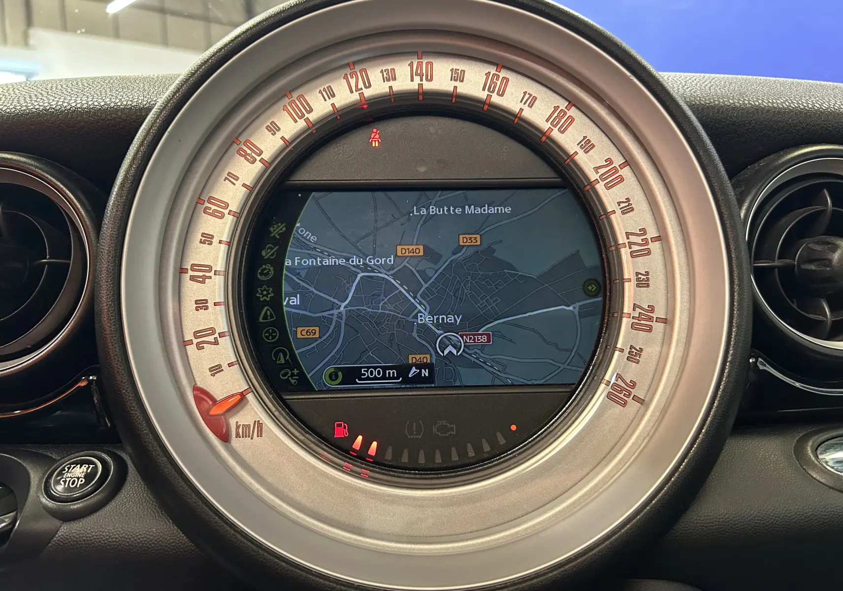Vue rapprochée du compteur central gris de la MINI Cooper 2011 avec écran de navigation affichant une carte.