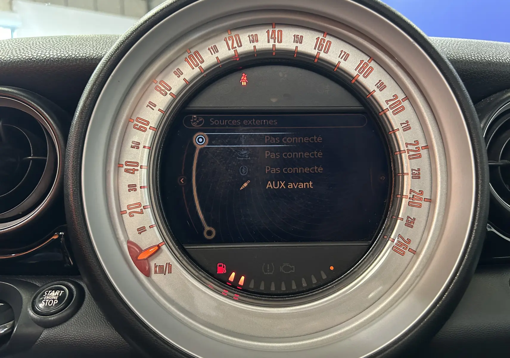Gros plan sur le compteur central gris de la MINI Cooper Diesel 2011, affichant l'interface multimédia et témoins lumineux.