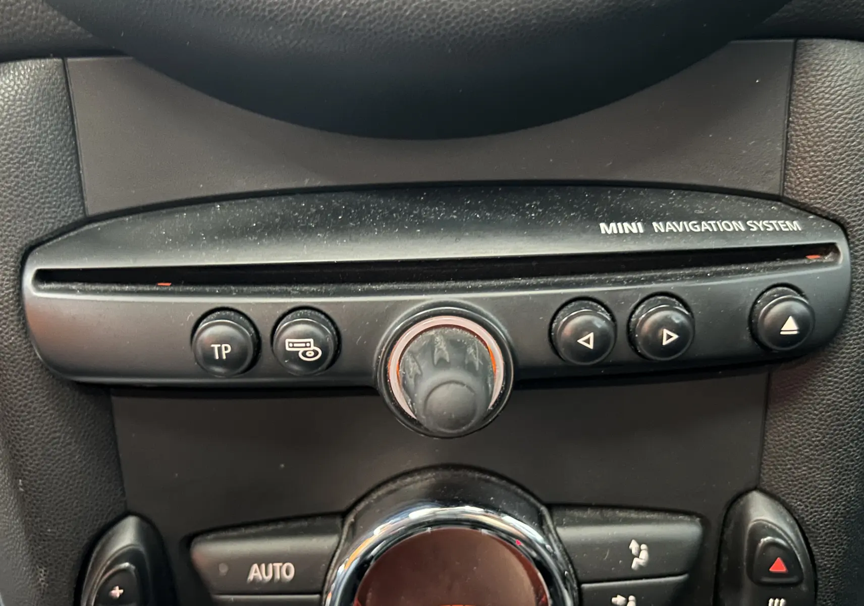 Gros plan sur la console centrale noire du MINI Cooper 2011, mettant en valeur le système de navigation et les commandes de climatisation.