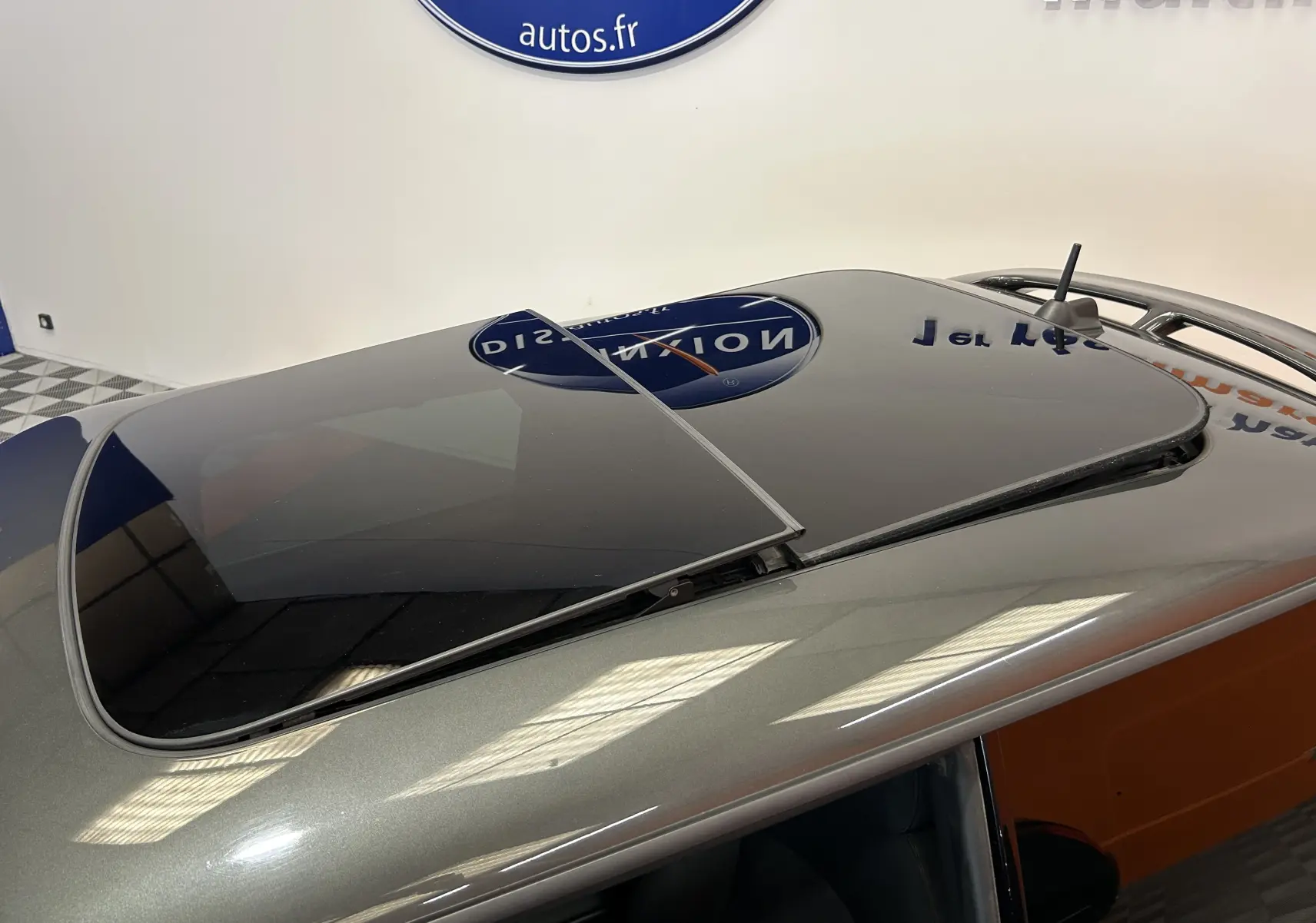 Toit ouvrant partiellement ouvert sur une MINI Cooper gris métallisé vue de dessus en intérieur showroom.