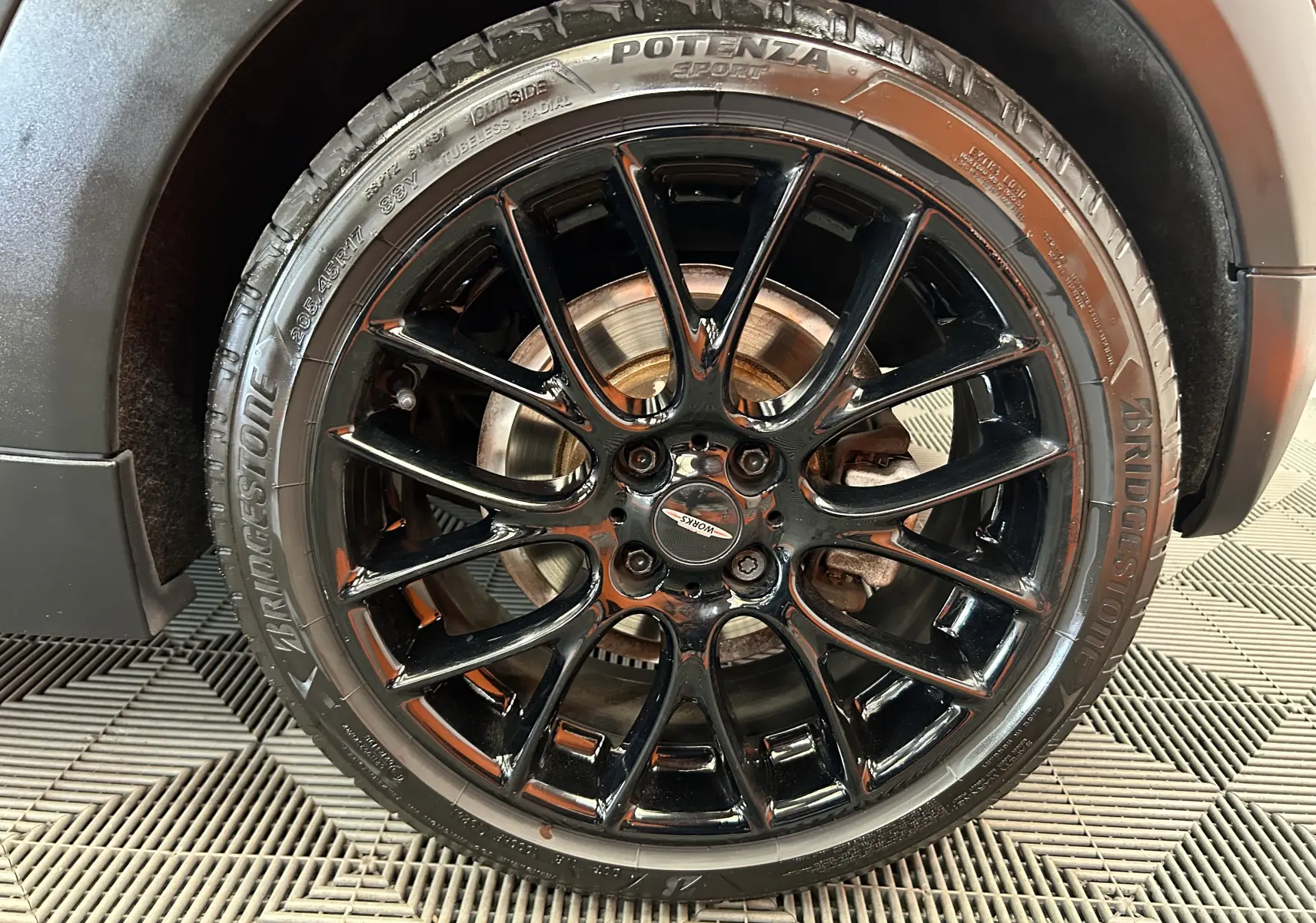 Gros plan sur la jante noire brillante de la MINI Cooper gris, mettant en valeur le pneu Bridgestone Potenza sport.