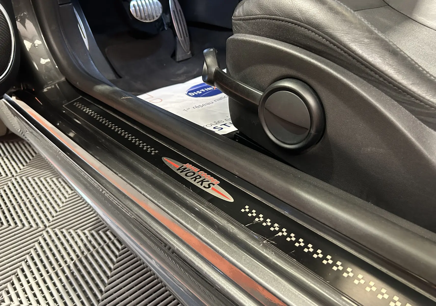 Vue intérieure côté gauche de la MINI Cooper gris avec seuil de porte marqué John Cooper Works et pédales sport en aluminium.