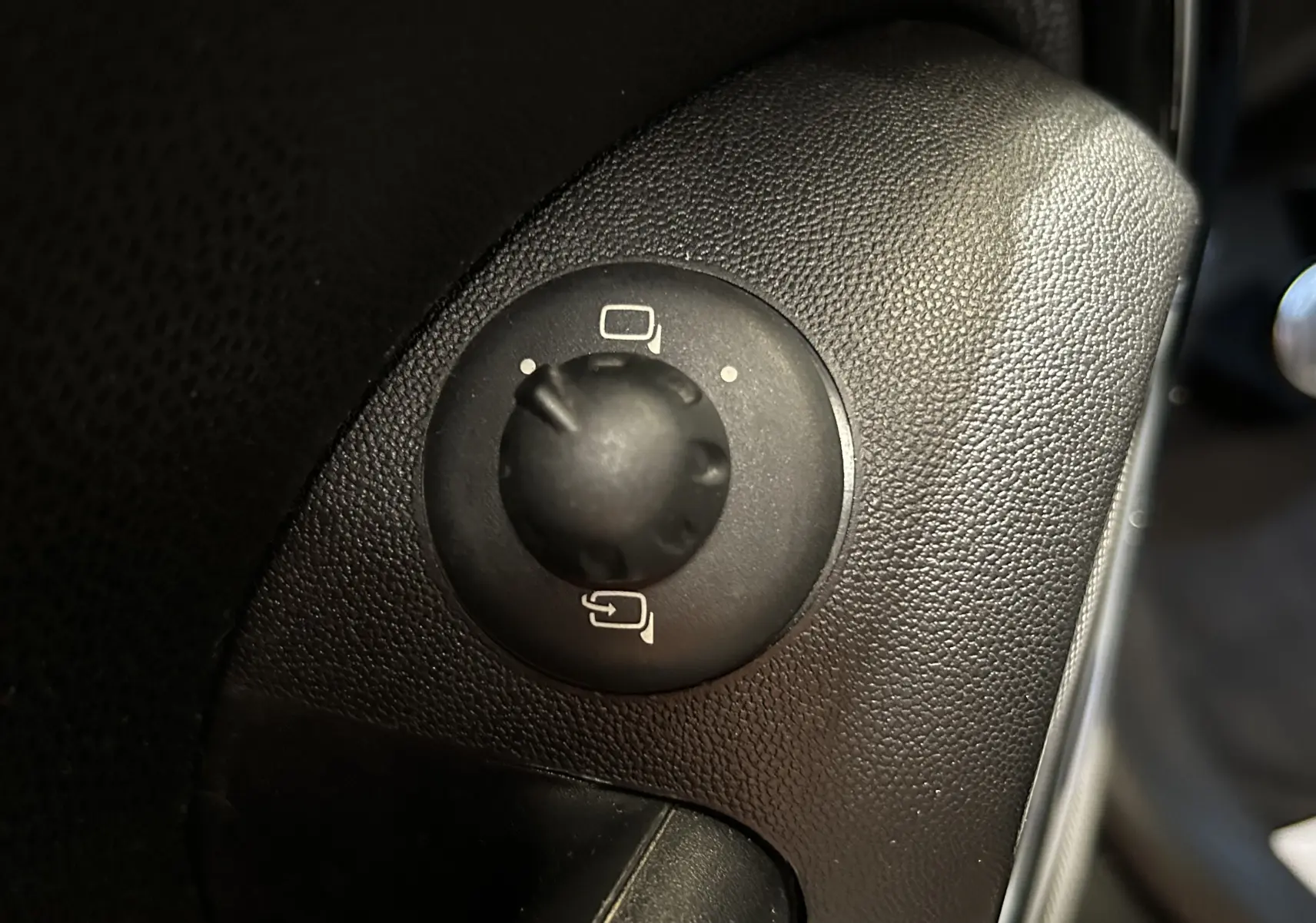 Gros plan sur le bouton de réglage des rétroviseurs noirs dans l'habitacle d'une MINI Cooper gris 2011.
