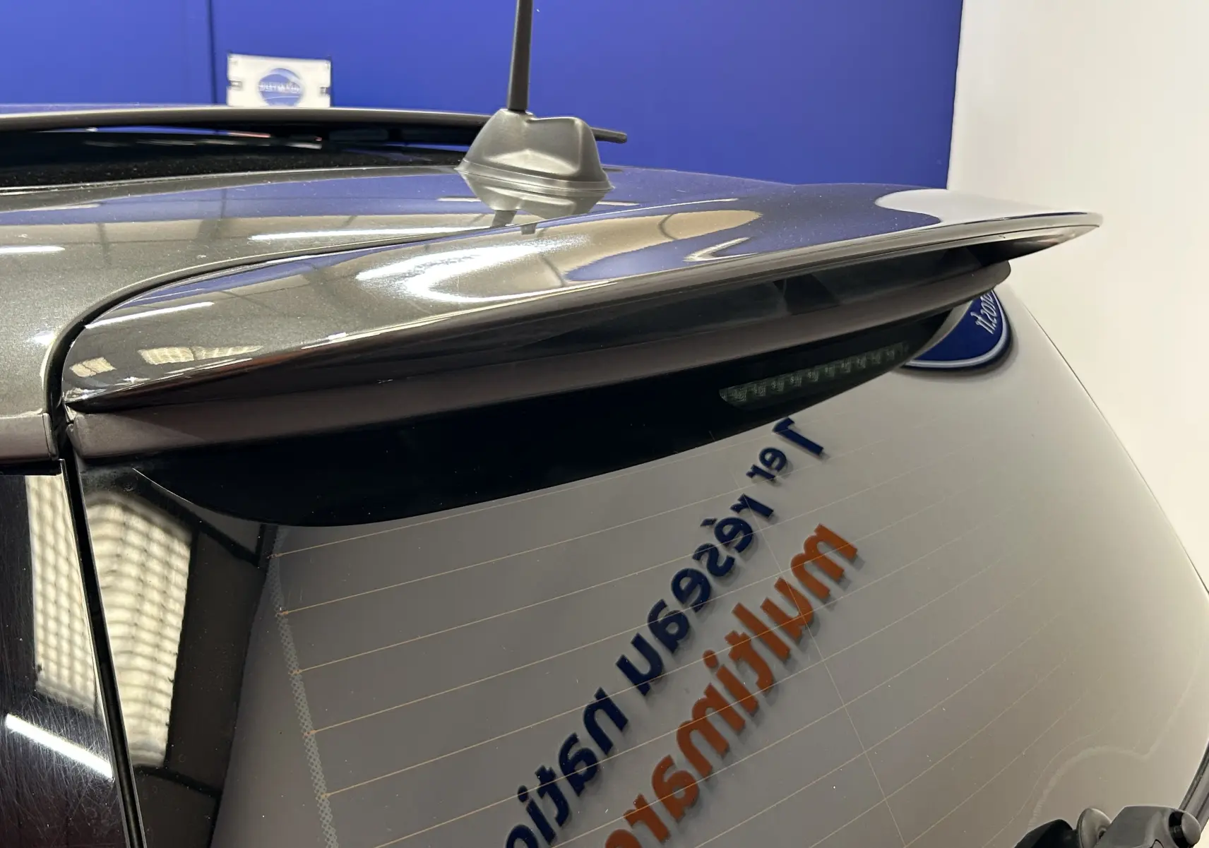 Vue rapprochée arrière droite d’une MINI Cooper gris métallisé avec aileron et antenne sur le toit.