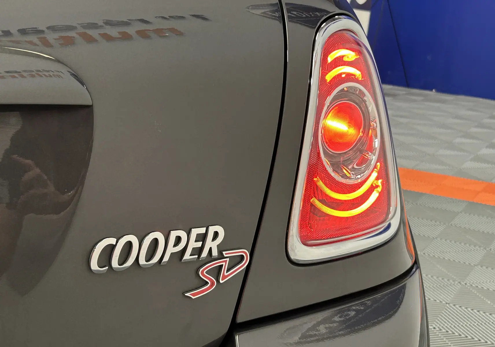 Gros plan sur le feu arrière droit allumé et le logo Cooper SD sur la carrosserie gris métallisé d'une MINI.