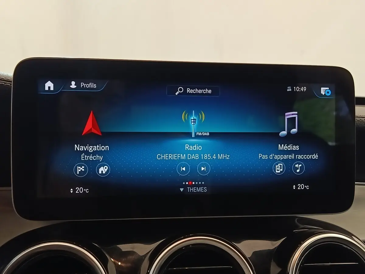 Écran tactile central du Mercedes GLC 300 bleu, affichant navigation, radio DAB et médias, avec aérateurs ronds chromés en dessous.