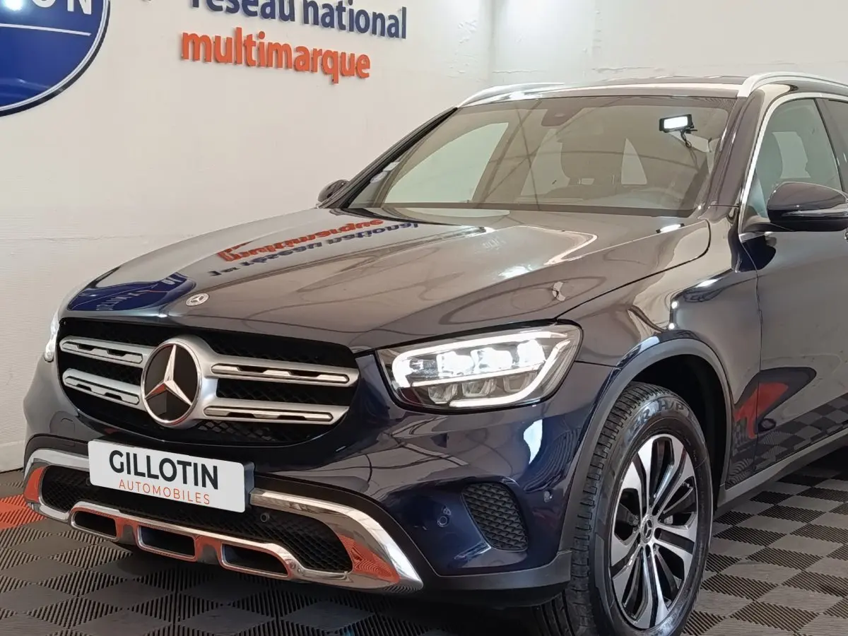 Vue 3/4 avant d’un Mercedes GLC 300 DE Business Line 4MATIC bleu avec calandre chromée et phares LED allumés.