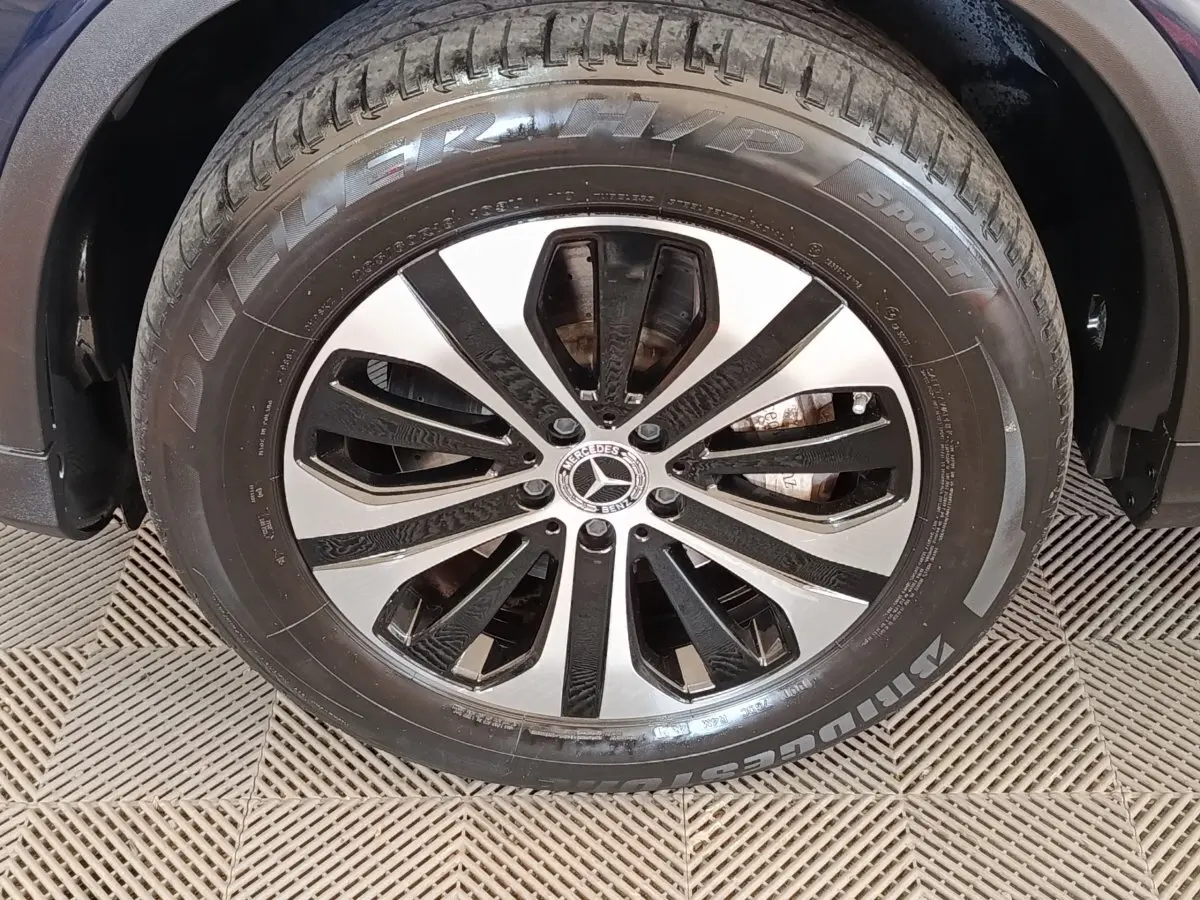 Gros plan sur la roue avant droite d’un Mercedes GLC bleu, avec jante alliage bicolore et pneu Bridgestone.