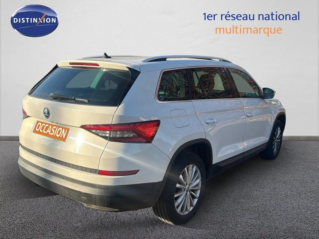 Vue 3/4 arrière droite d'un Skoda Kodiaq blanc 2018 avec jantes alliage et toit ouvrant visible.