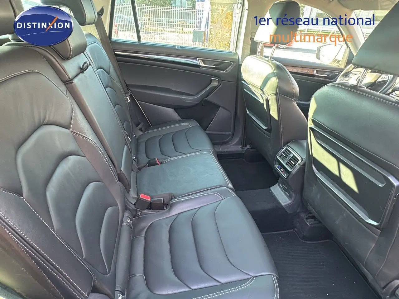 Vue intérieure sur la banquette arrière en cuir noir du Skoda Kodiaq blanc, mettant en valeur l'espace et les finitions soignées.