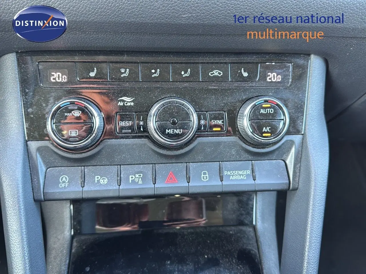 Vue rapprochée du tableau de bord central du Skoda Kodiaq blanc, montrant les commandes de climatisation et les boutons de sécurité.