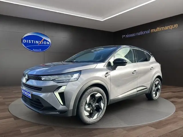 Vue 3/4 avant droite du Renault Captur 2025 gris Cassiopée avec toit noir et jantes distinctives, en présentation showroom.