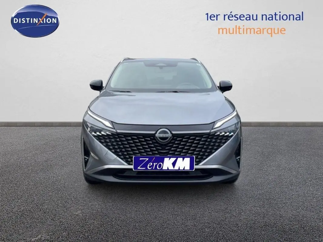 Vue avant d'un Nissan Qashqai gris 2025 avec calandre noire et feux LED fins allumés.