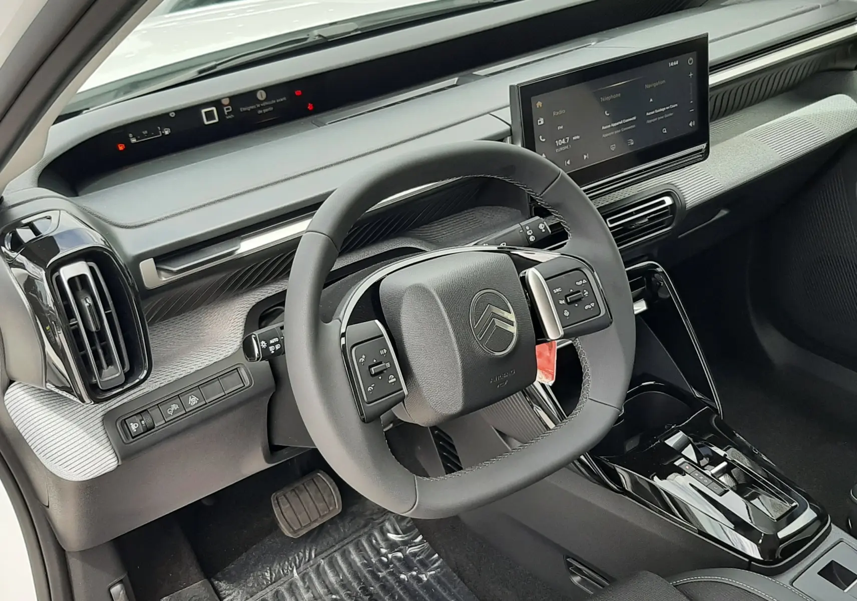 Vue intérieure du poste de conduite de la Citroën C3 Aircross blanc banquise, volant multifonctions et écran tactile central.
