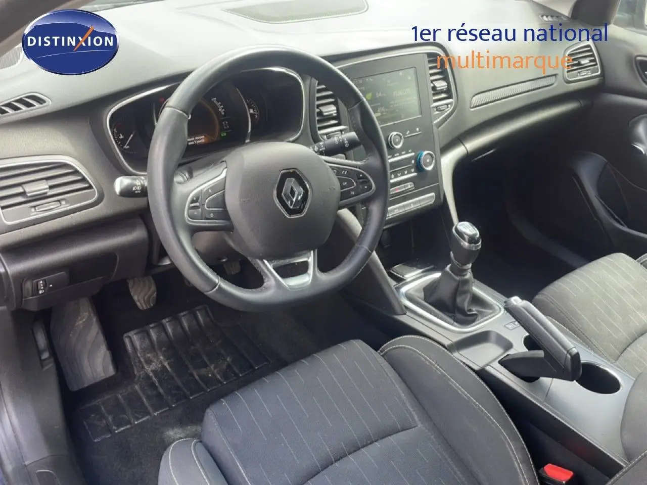 Intérieur de Renault Mégane 2021 vu côté conducteur, volant cuir, tableau de bord avec écran tactile et levier de vitesse manuel.